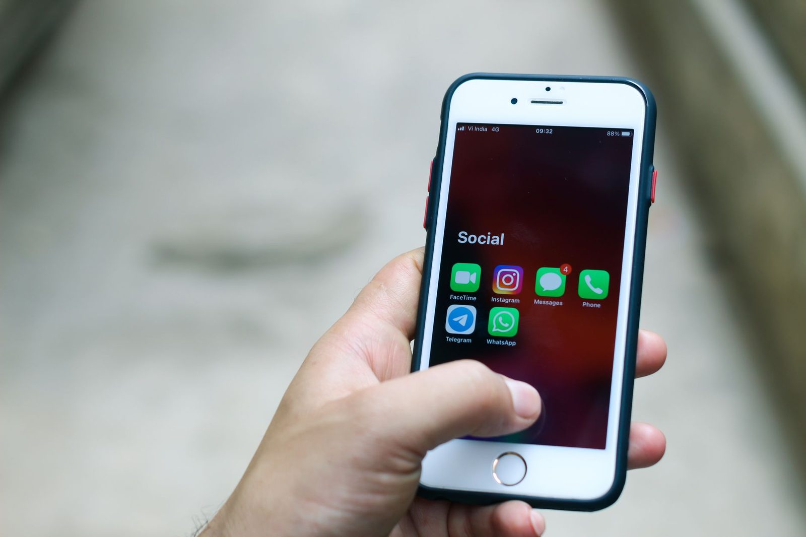 Mano che tiene un iPhone con aperta una cartella di app di messaggistica, tra cui Messaggi con 4 notifiche