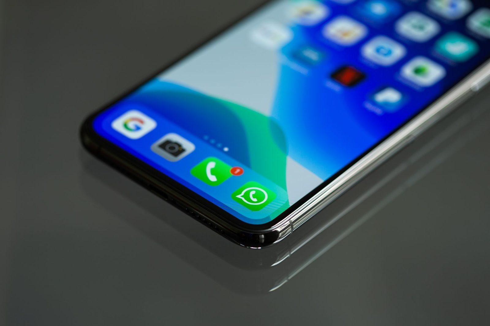 Primo piano di uno smartphone appoggiato su una superficie nera, con le icone di Google, telefono e messaggi in evidenza