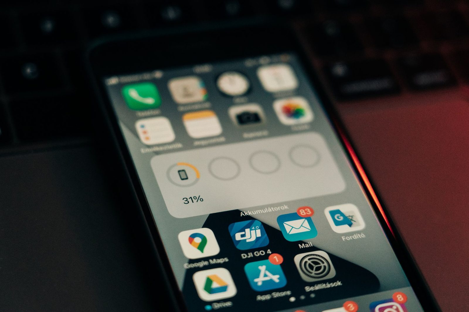 Gros plan d'un smartphone posé sur un clavier, écran d'accueil affichant des applications dont Mail et Messages