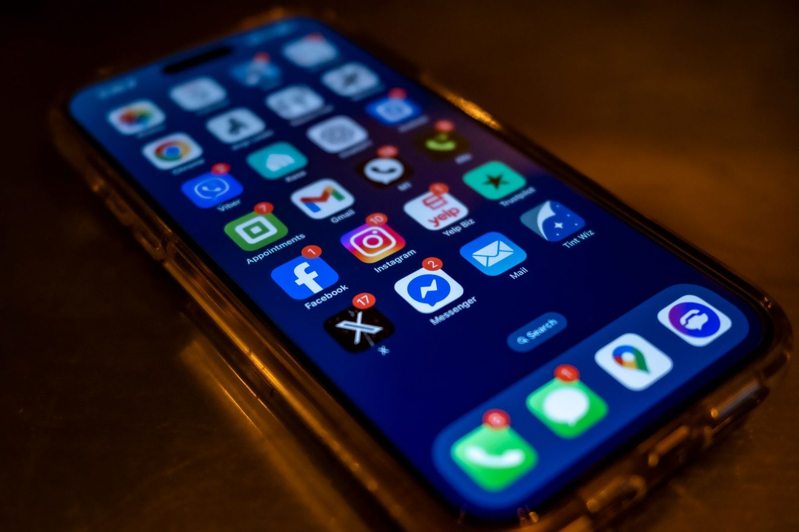 Smartphone posé sur une table, écran d'accueil allumé avec des applications de messagerie et des notifications