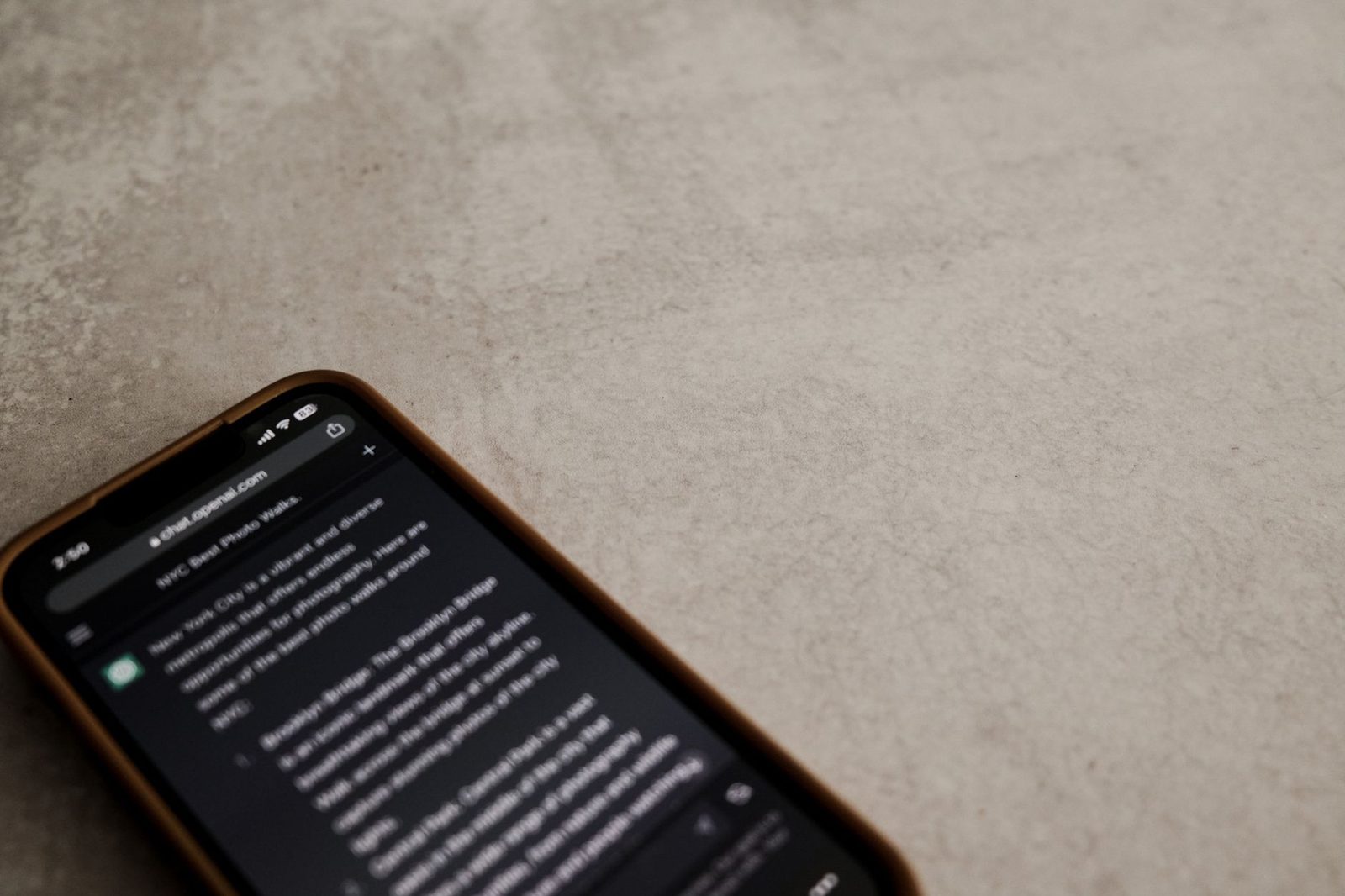 Smartfon leżący na betonowej powierzchni, z włączonym ekranem wyświetlającym tekst w przeglądarce