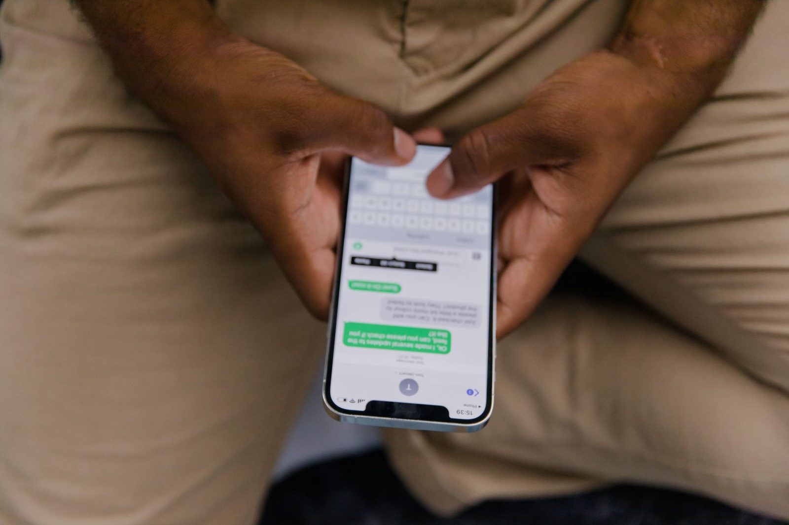 Man sitting holding a smartphone displaying a text message conversation