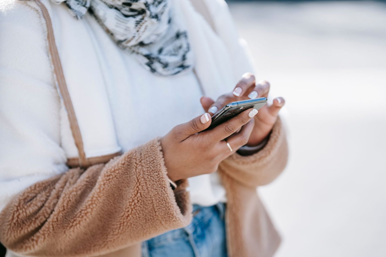 Close-up of a woman's hands holding a smartphone outdoors