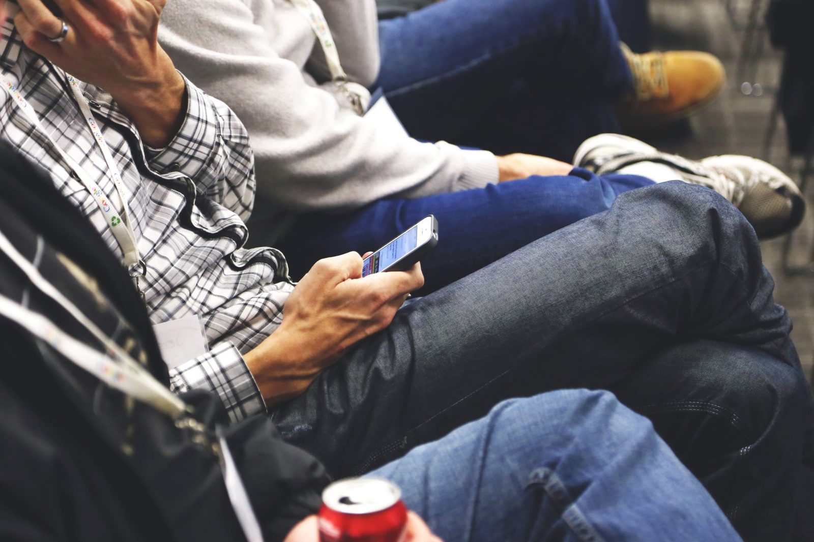 Personne assise consultant un message sur son smartphone, entourée d'autres participants