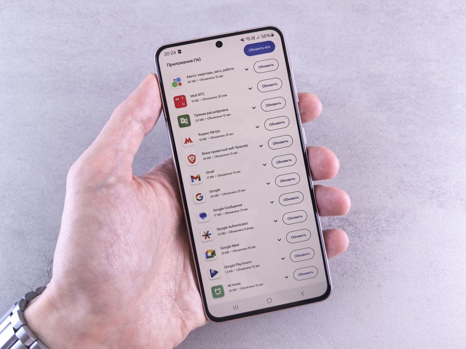 Hand holding a smartphone showing the list of apps waiting to be updated on its screen