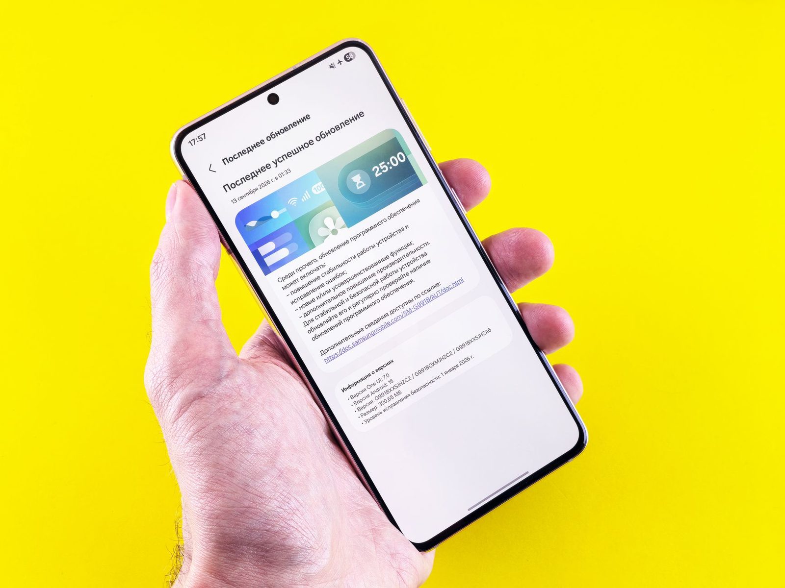 Hand holding a smartphone showing the software update screen, against a bright yellow background